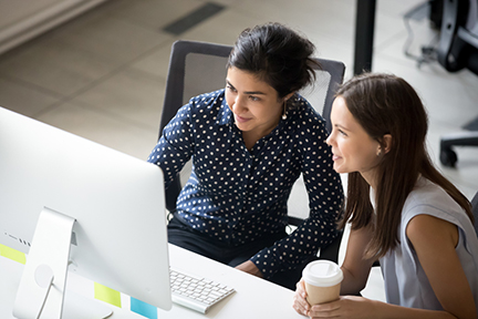 Two young women, looking at a computer smiling